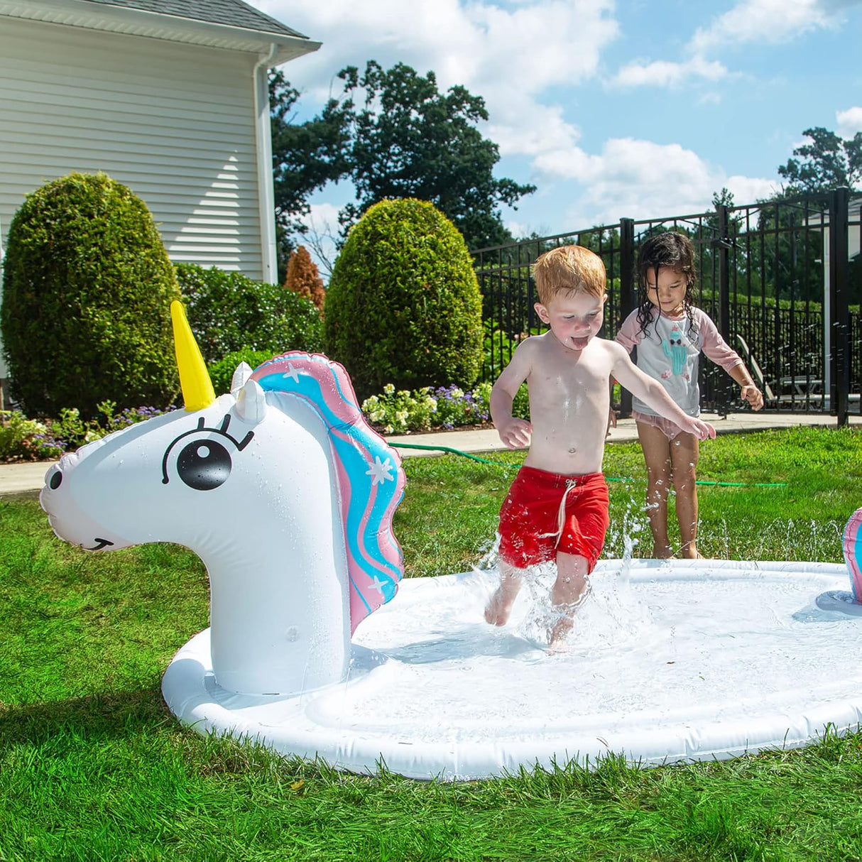 Splash Pad Sprinkler Unicorn with kids playing and splashing in a 6-foot inflatable water park in the backyard.