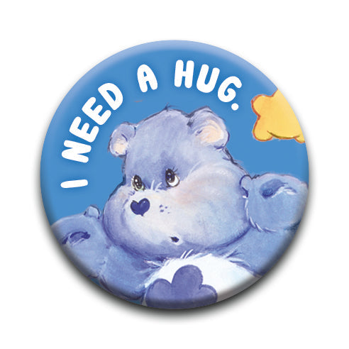 Care Bears Grump Button pin featuring a blue bear with "I need a hug" text on a blue background, 1.25 inch size.