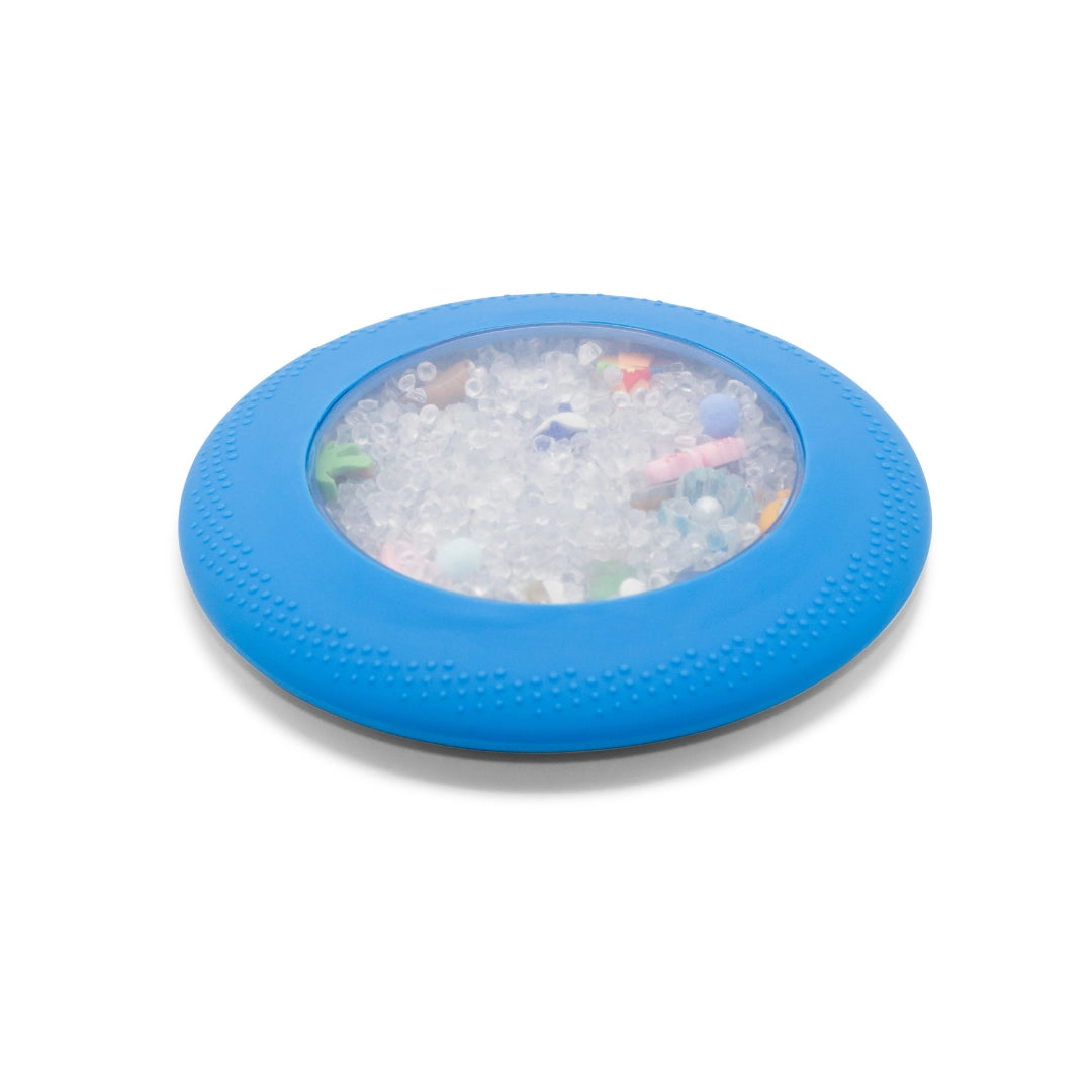 Round blue rubber disc with clear center filled with small white beads and colorful bits inside