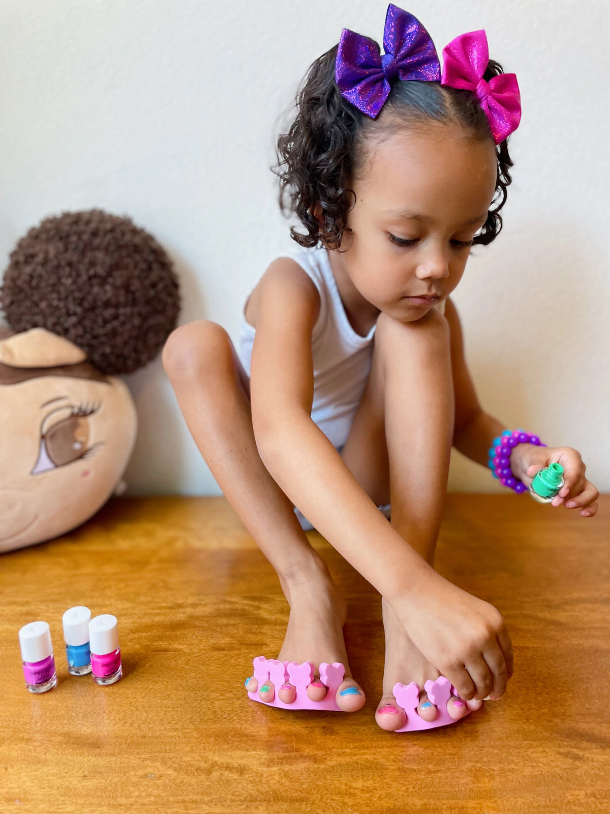 Lil Piggy Pedicure Set with pink toe separators and nail polish bottles beside a child