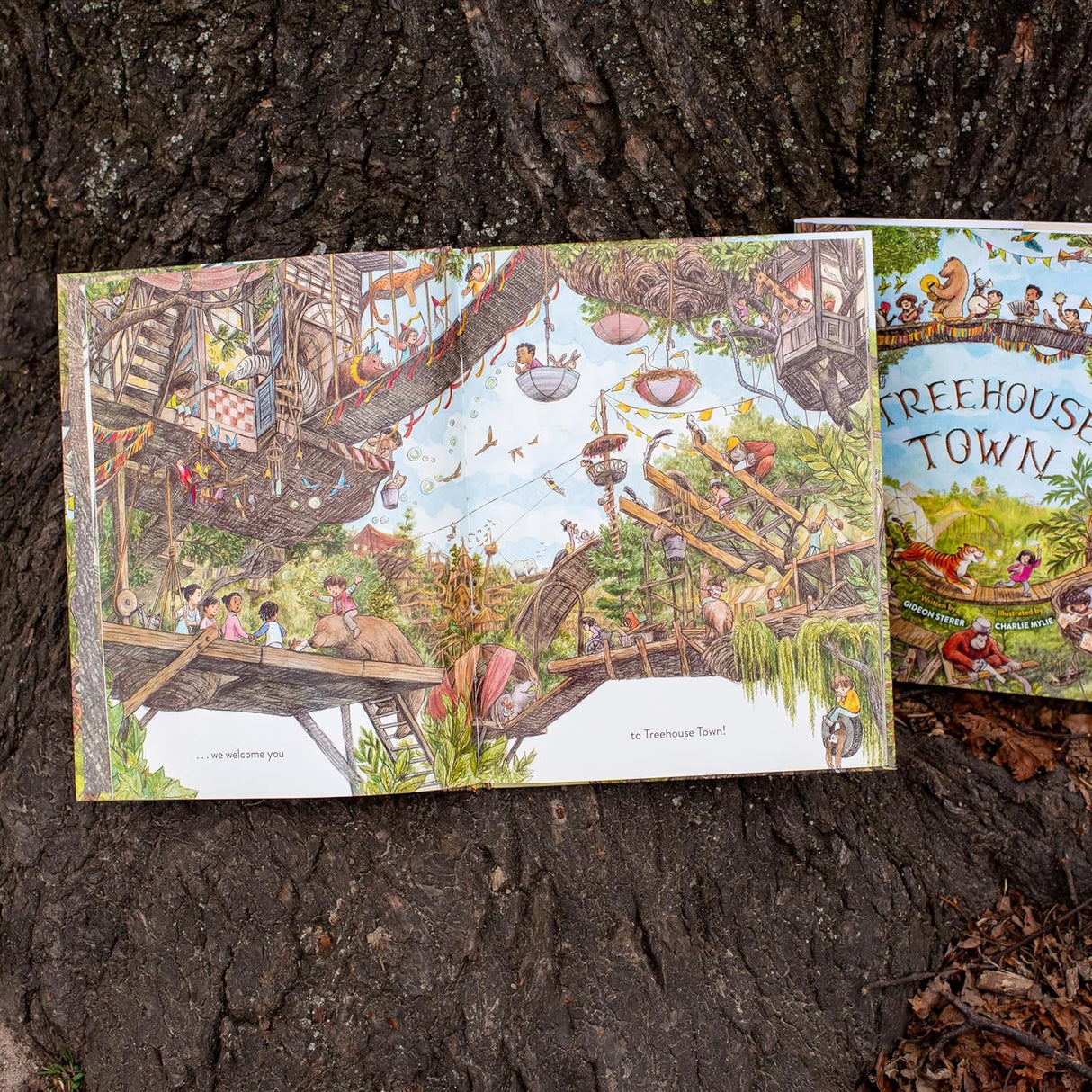 Open pages of Treehouse Town show detailed illustrations of a vibrant treetop world with children and animals exploring.