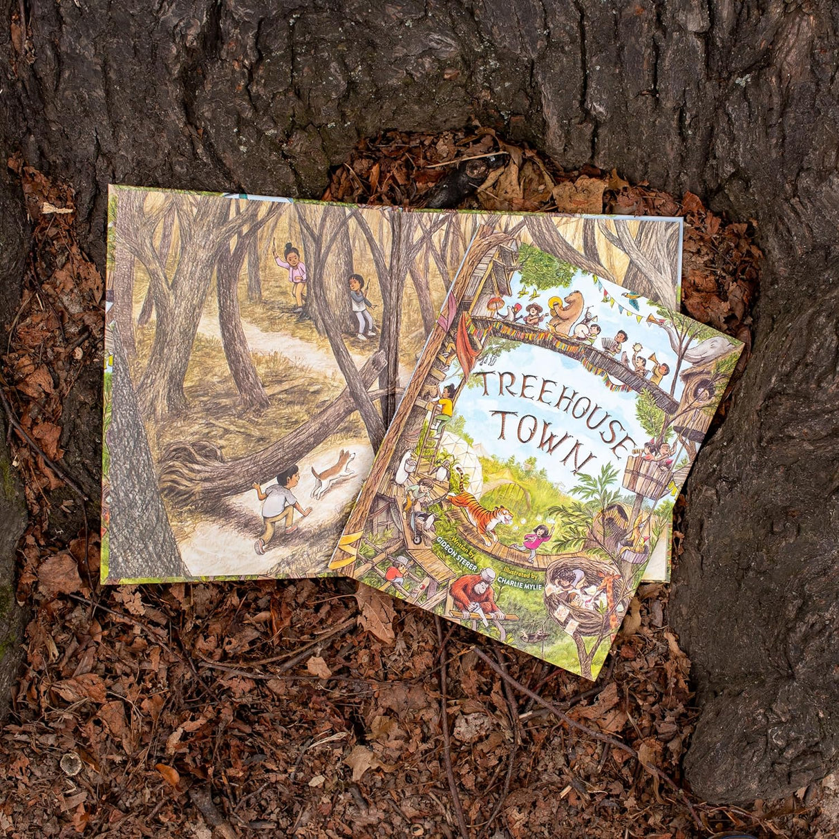 Treehouse Town picture book laying open on tree bark, showing detailed illustrations of children playing in a forest.