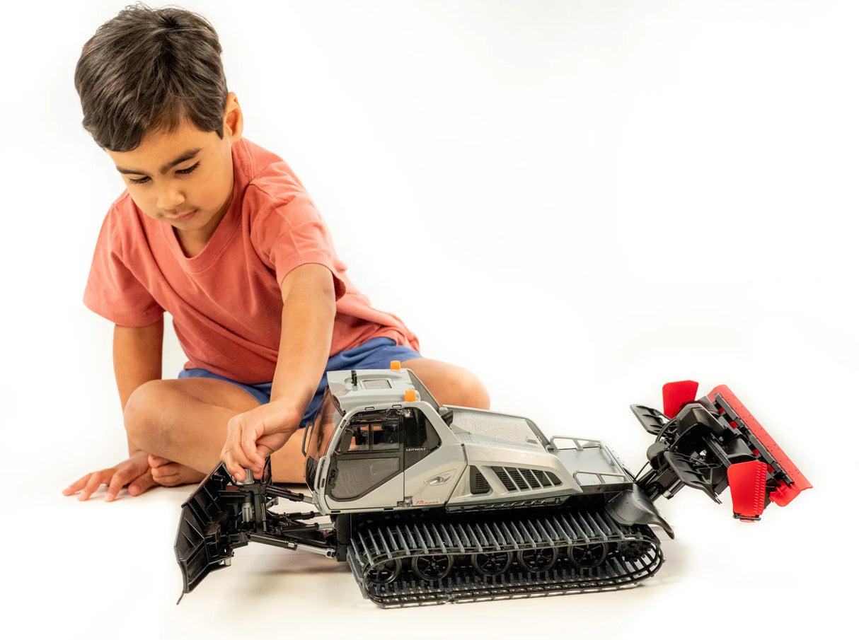 Child playing with a detailed Prinoth Snow Groomer toy model with adjustable blades and snow blower features.