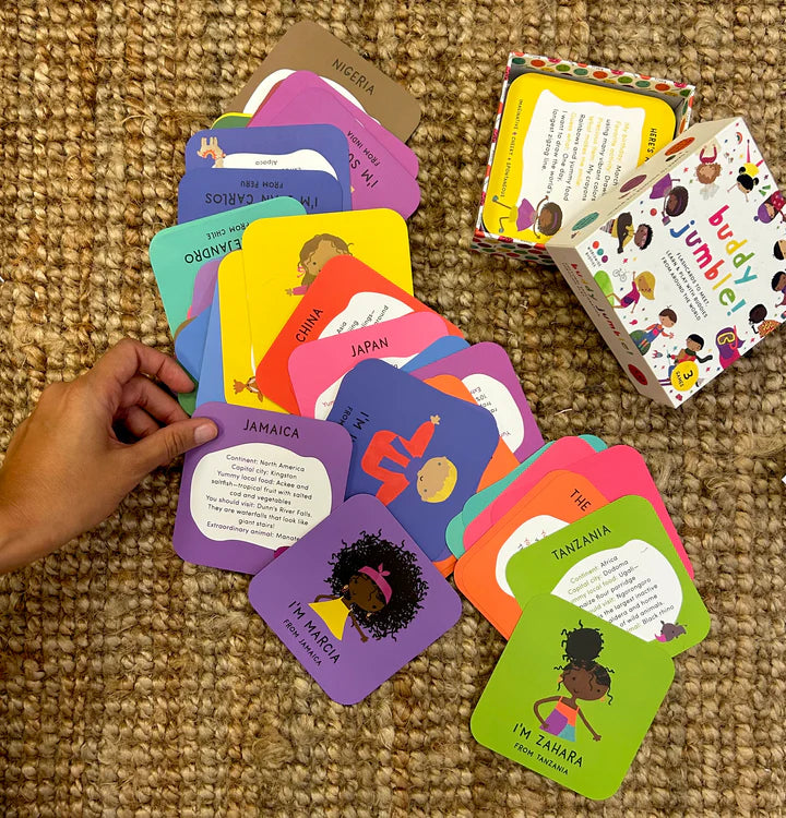 A pile of colorful cards from the game "Buddy Jumble" spread out over a carpet.