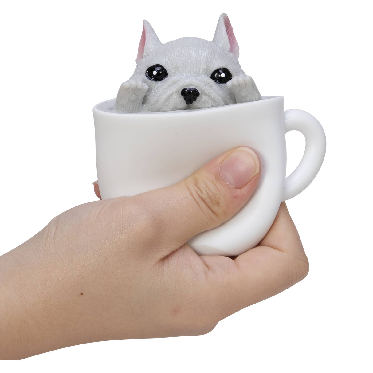Pup in a Cup showing a white puppy squishy toy popping out of a white espresso cup held in a hand.