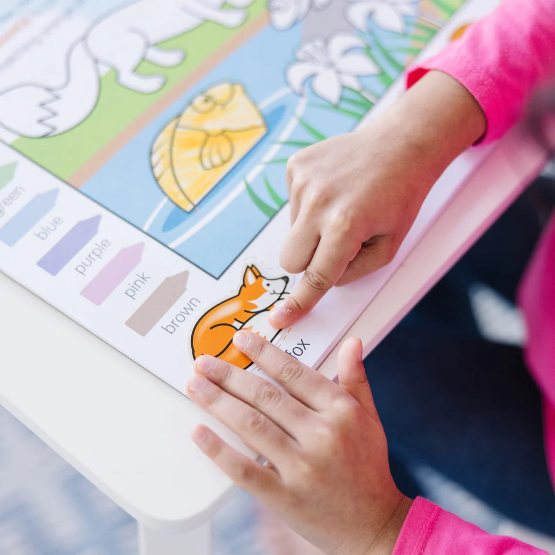 Child interacting with a colorful page featuring animals and colors from the Colors & Shapes Activity Pad.