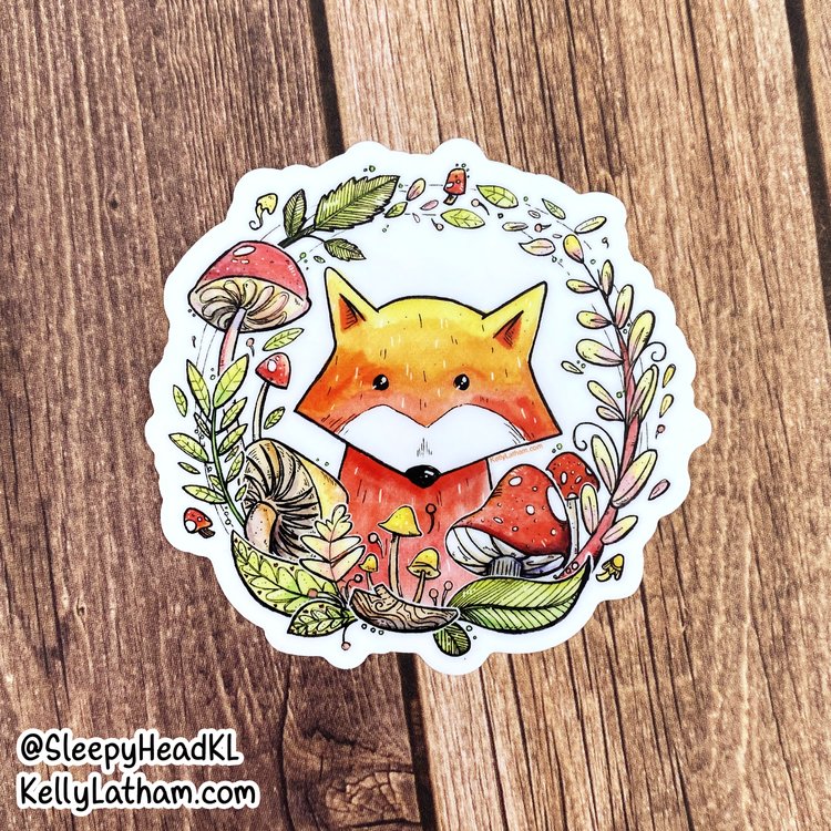 Fox & Mushroom Wreath Sticker featuring a cute fox surrounded by colorful mushrooms and leaves on a wooden background.