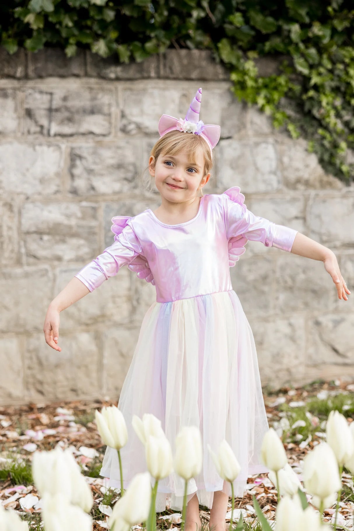 Smiling girl wearing Alicorn Dress & Wings & Headband in iridescent fabric with flowing tulle skirt outdoors.