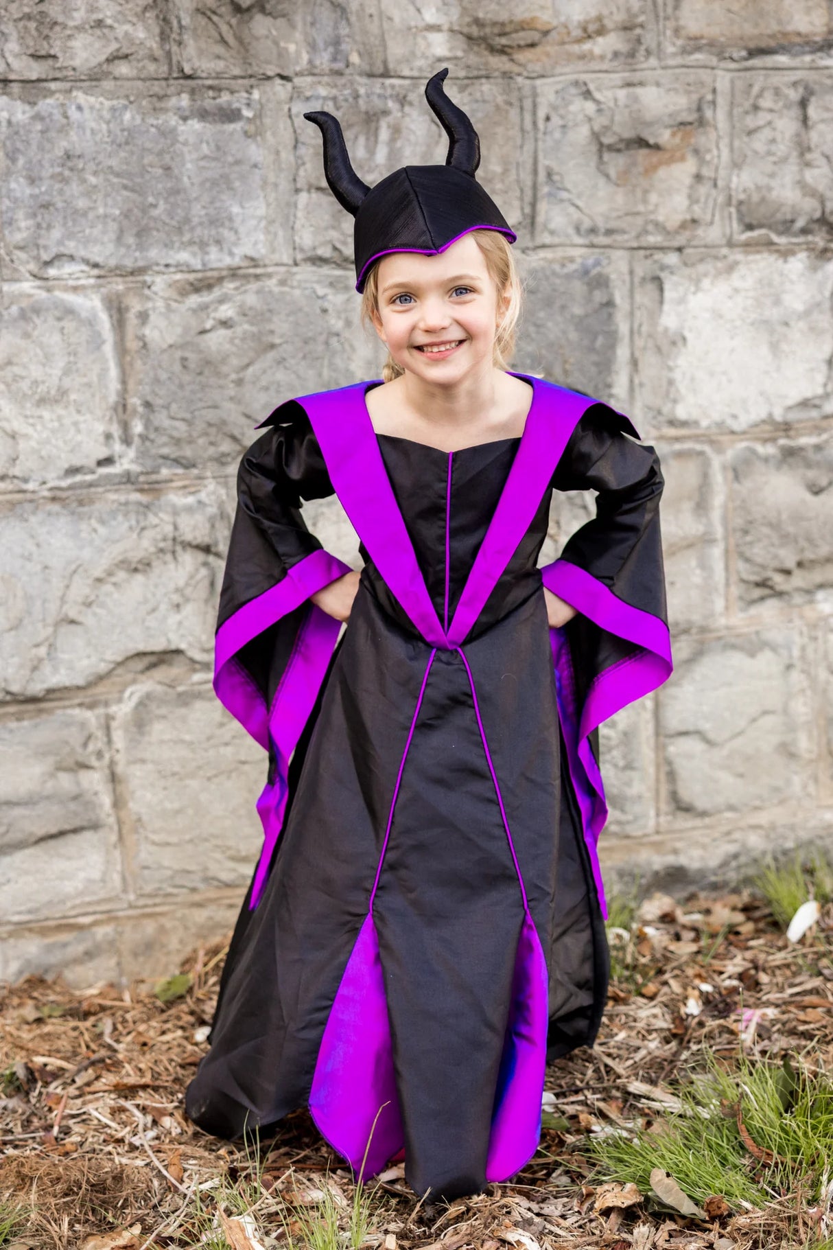 Young girl wearing Villain Princess Dress & Headpiece Size 5-6 in black and purple with horned headpiece outdoors.