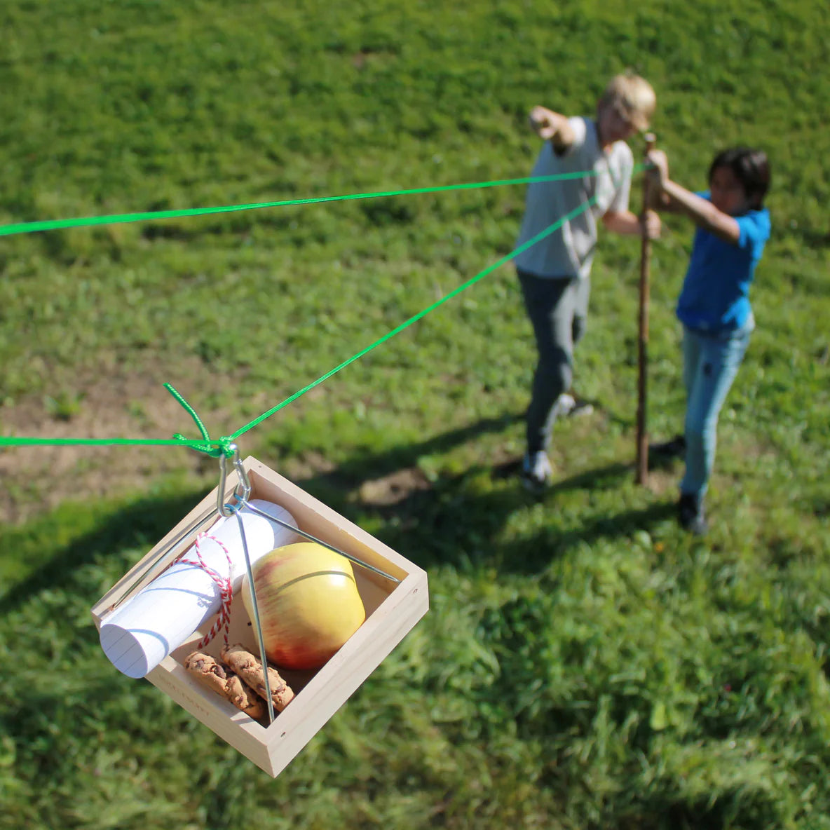 Huckleberry Cable Transport carrying messages and items between two people outdoors on a green rope line.