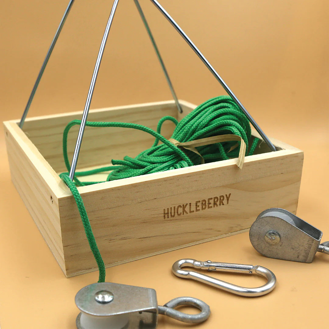 Huckleberry Cable Transport wooden box with green rope, metal pulleys, and carabiner for cable message sending.