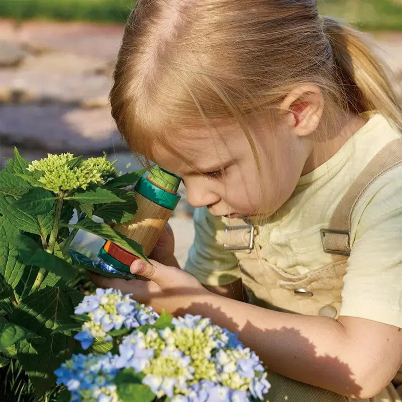 Young child examining plants outdoors using a portable Field Microscope with LED light and magnification.