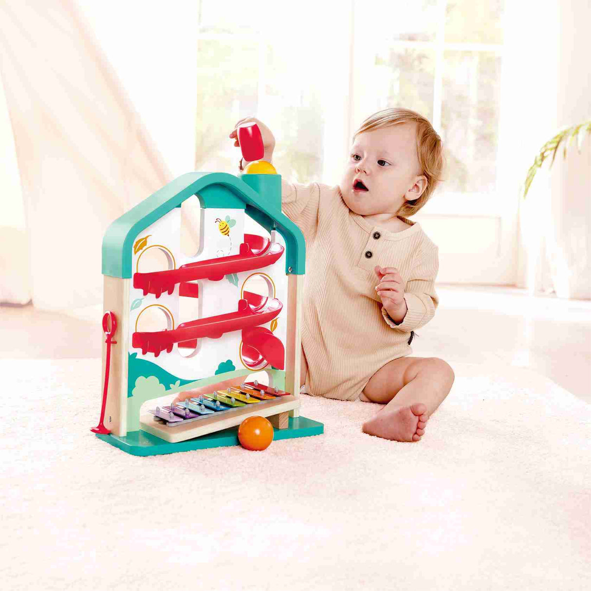 Baby playing with the Melody Mansion Ball Run, a colorful house-shaped ball rolling game with xylophone sounds.