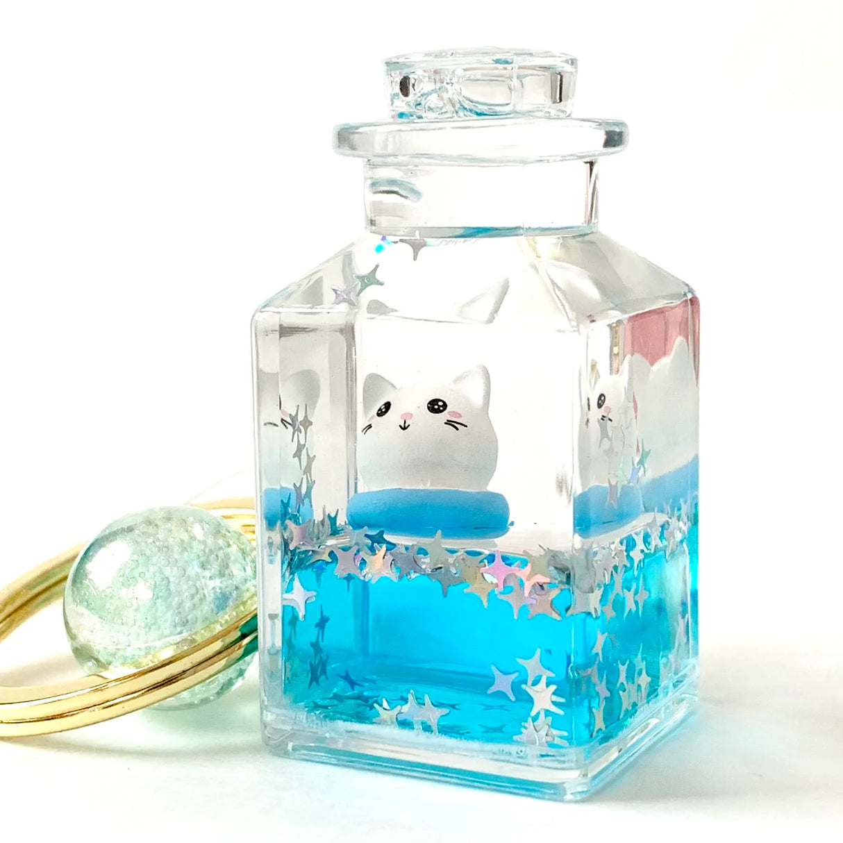 Kitty Jar Floaty KeyChain featuring a floating cat in a clear jar with blue liquid and star-shaped glitter inside.