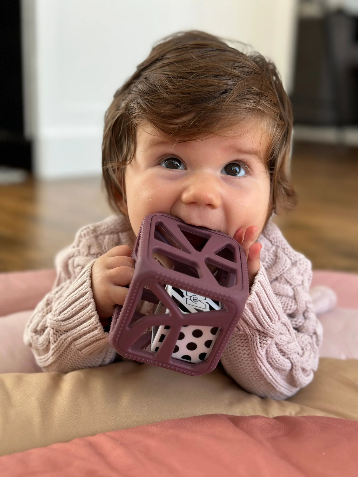 Baby chewing on a purple teething toy with textured surfaces, specifically the Chew Cube | Purple teething rattle.