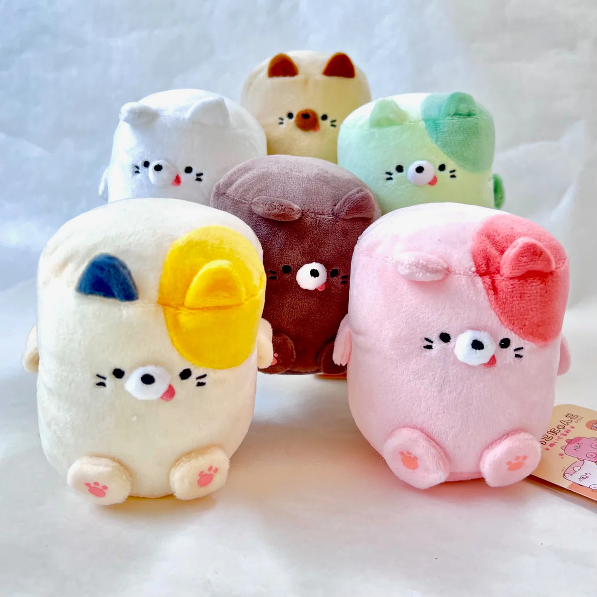 Plush Marshmallow Cat toys in assorted colors with cute faces and toe bean details, each sold separately.