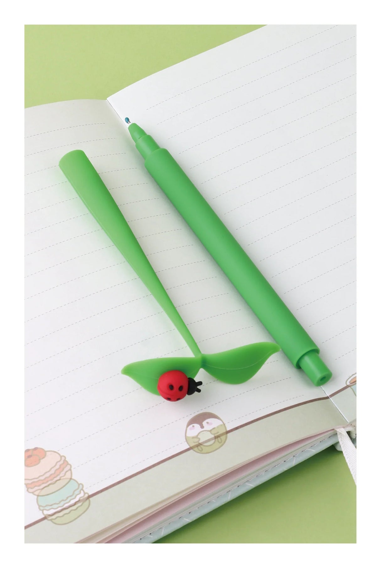Bug on Leaf Wiggle Gel Pen with green leaf cap and ladybug detail, smooth fine tip black gel ink pen on notebook.