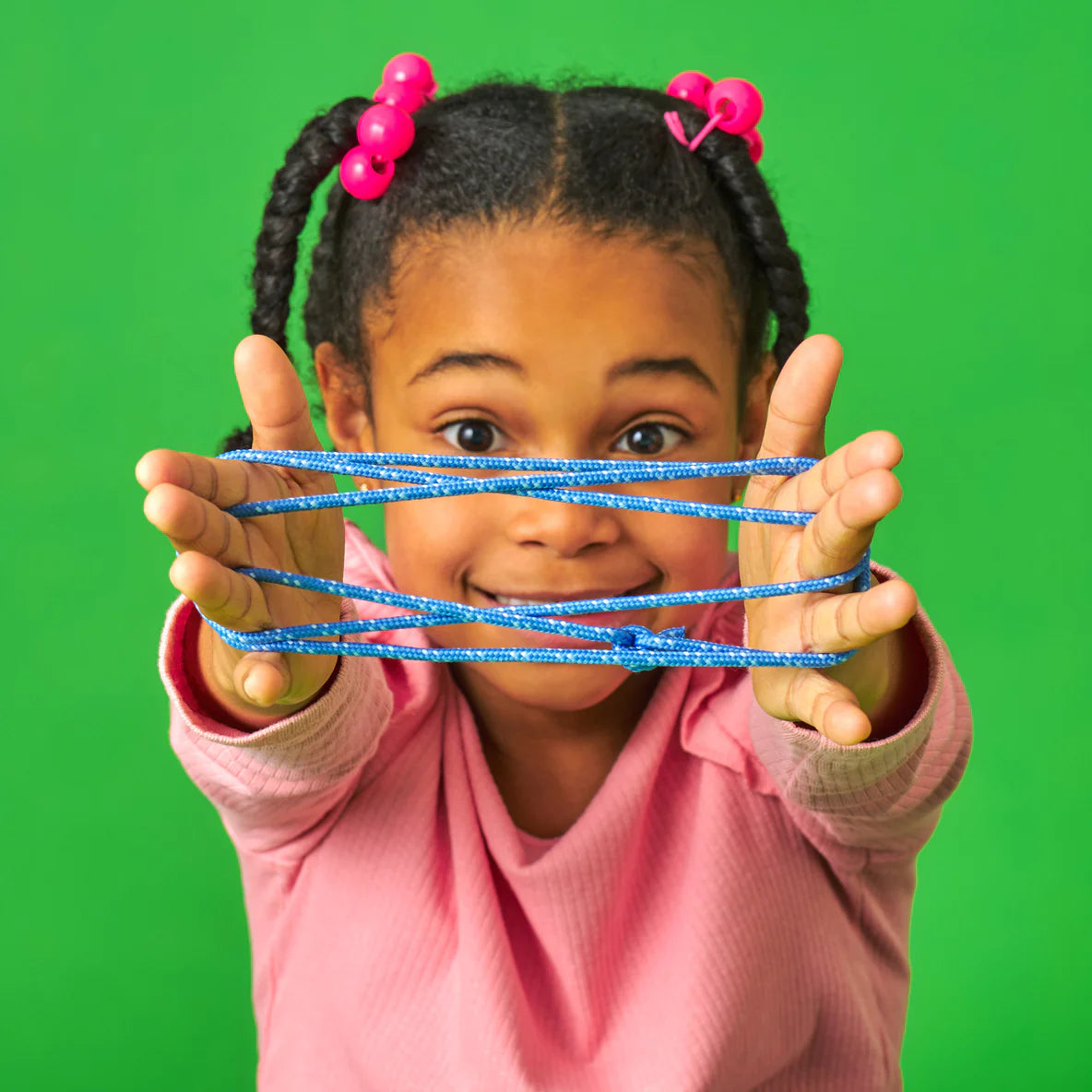 Girl playing with blue string creating a pattern in Kidoki Cat's Cradle game against a green background