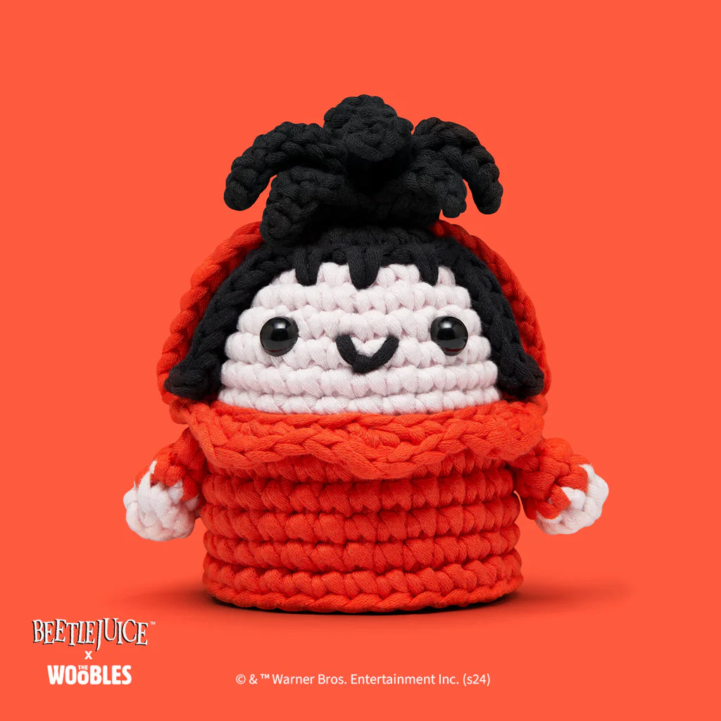 Crocheted figure of Lydia from Beetlejuice wearing a red dress with black hair and a spider on her head