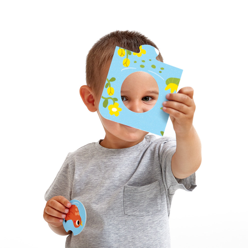 Child holding blue puzzle piece with circular cutout from Match the Farm Animals Puzzle educational set.