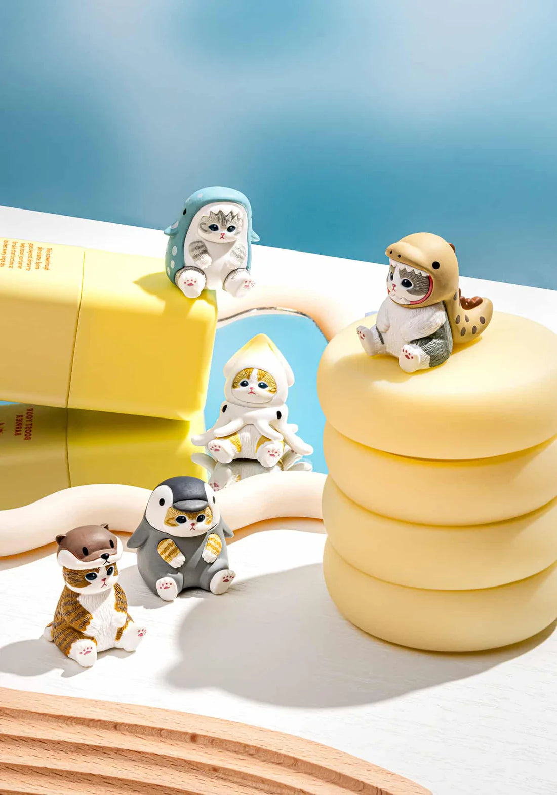 Five miniature cat figures dressed in whimsical sea animal costumes displayed on a white surface with blue background