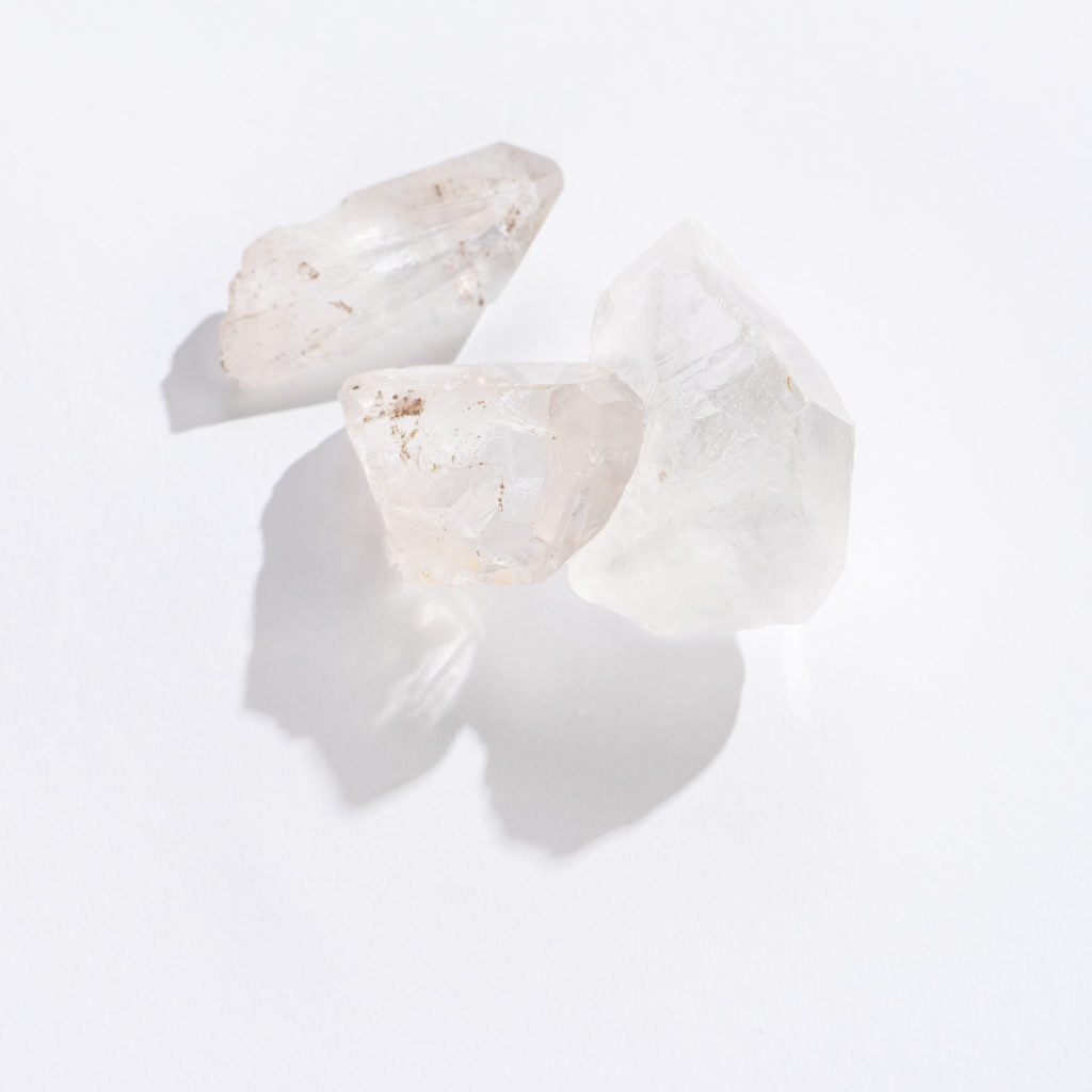 Three clear quartz point crystals with natural imperfections on a white background, Rock | Clear Quartz Point.