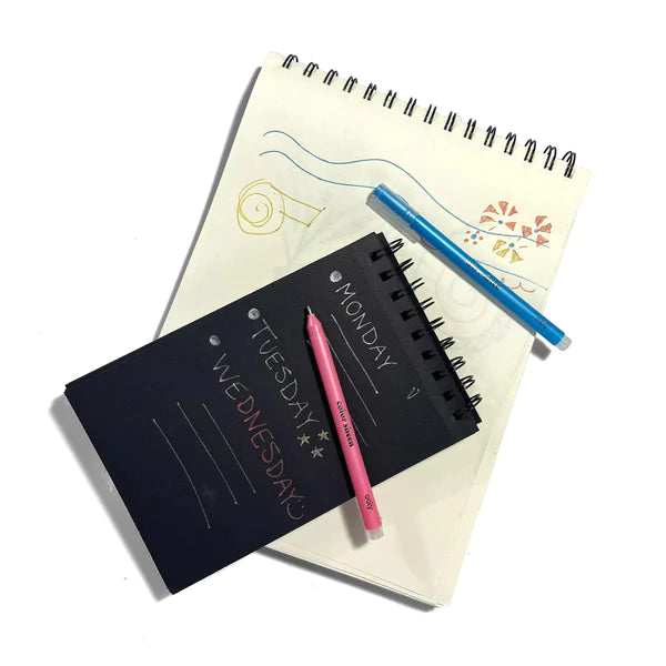 Color Sheen Metallic Gel Pens writing on black and white notebooks with blue and pink pens displayed.