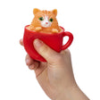 Hand squeezing red cup with orange kitten popping out in Pop a Chino Kitties! collectible toy series.
