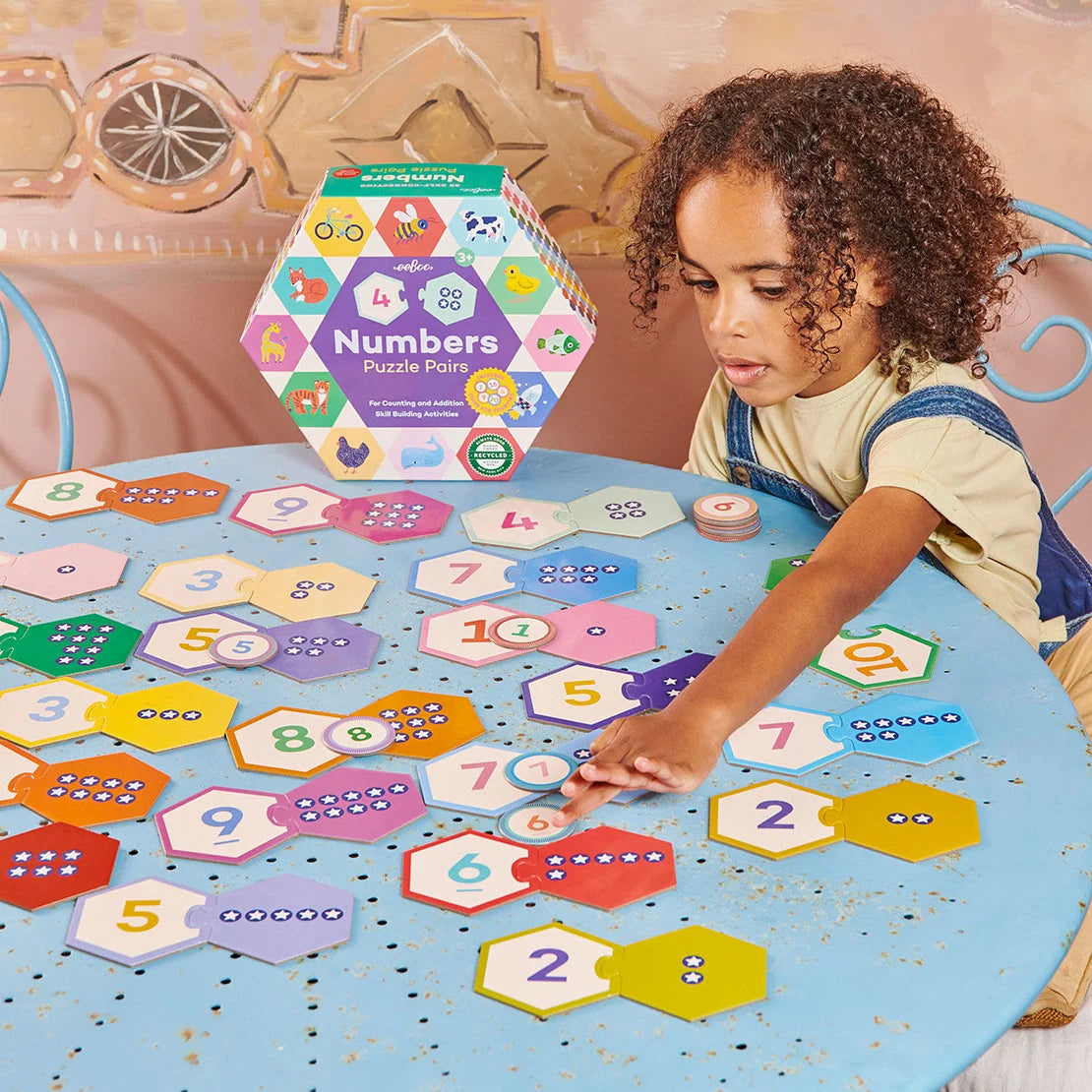Numbers Puzzle Pairs educational game with child matching colorful numbered and counting tiles on a table