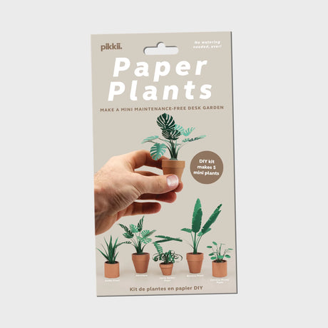 Hand holding miniature DIY paper plant with four other small paper plants in terracotta pots on beige background