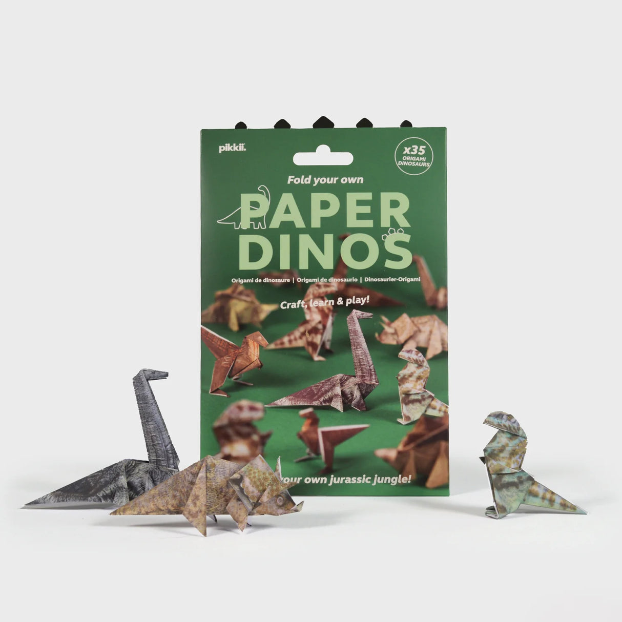 Origami kit featuring fold-your-own realistic paper dinosaurs displayed in front of a green themed packaging box.