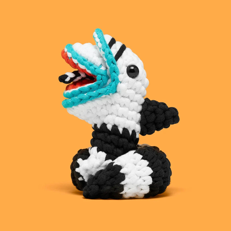 Handcrafted black and white plush toy with bright blue and orange accents on a solid orange background