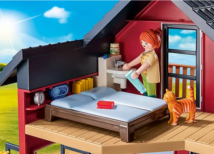 Country | Farmhouse with Outdoor Area Playmobil set showing a figure cleaning beside bed with a cat on the wooden porch.