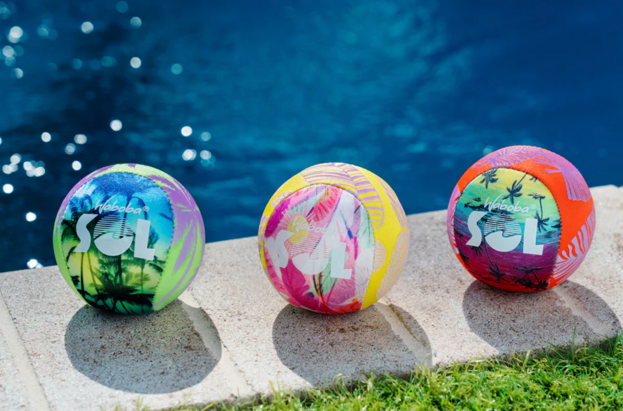 Three colorful Waboba SOL Balls with UV color-changing ink resting by a pool, designed to bounce on water.