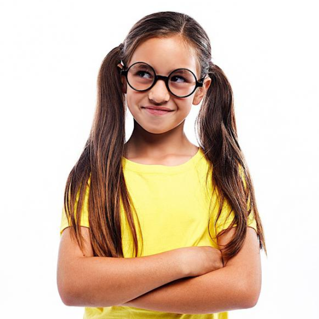 Young girl with long hair wearing Harry Potter glasses and a yellow shirt, smiling confidently with arms crossed.