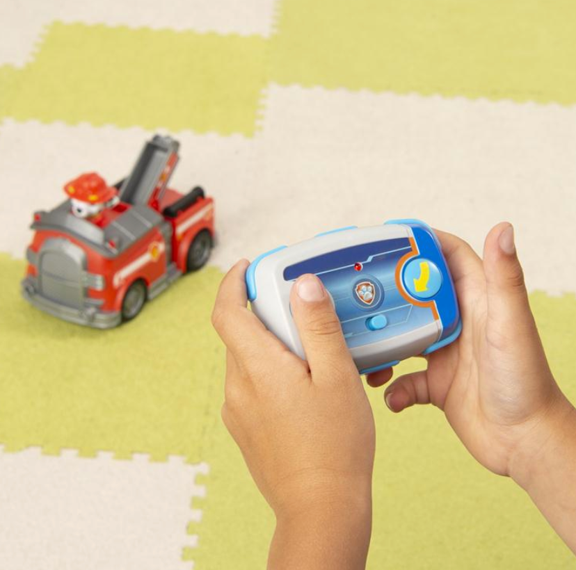 Child playing with remote control driving the RC Paw Patrol Marshall Fire Truck on a play mat surface