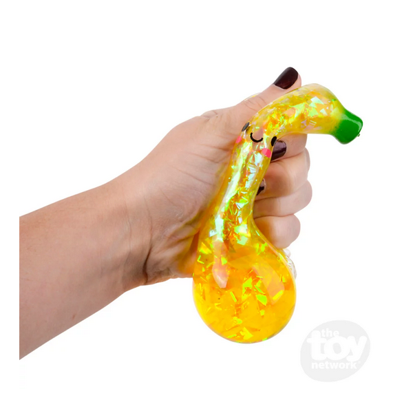Hand squeezing the sparkly liquid-filled Squeeze Sparkle Banana for fun sensory play and stress relief.