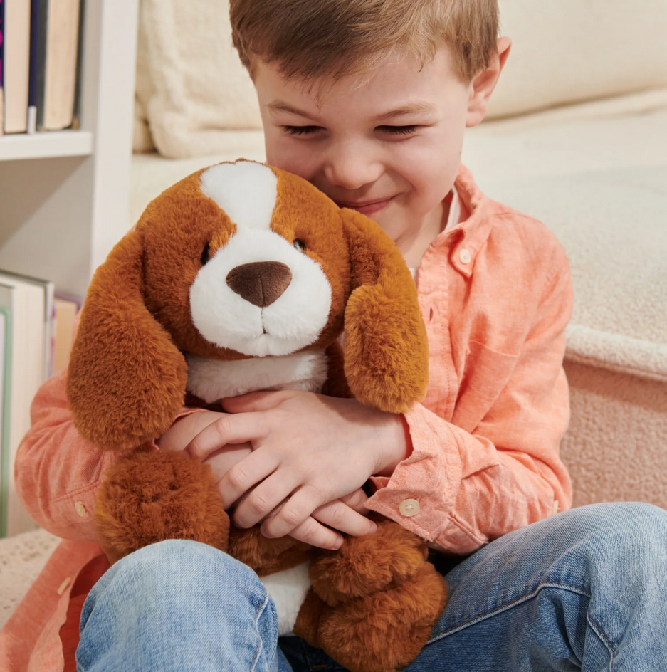 Child hugging a soft plush dog Spaniel Kian with high-pile copper fur and floppy ears, sitting upright and cuddly.