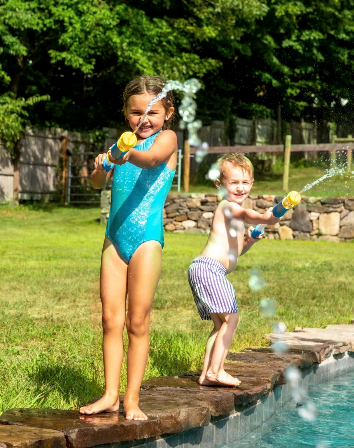 Two kids having fun by the pool using the Water Cannon | Magenta to spray water and play in the sun.
