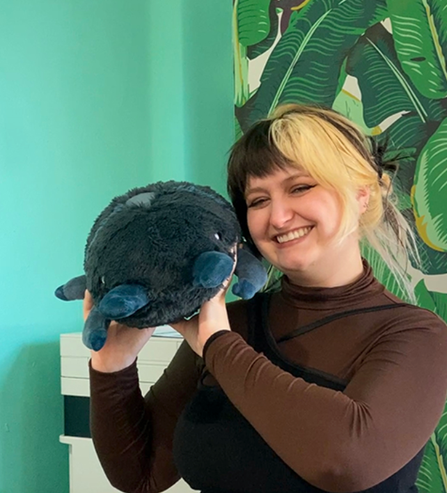 Smiling woman holding the plush Stag Beetle Mini, a soft polyester fiber toy for all ages.