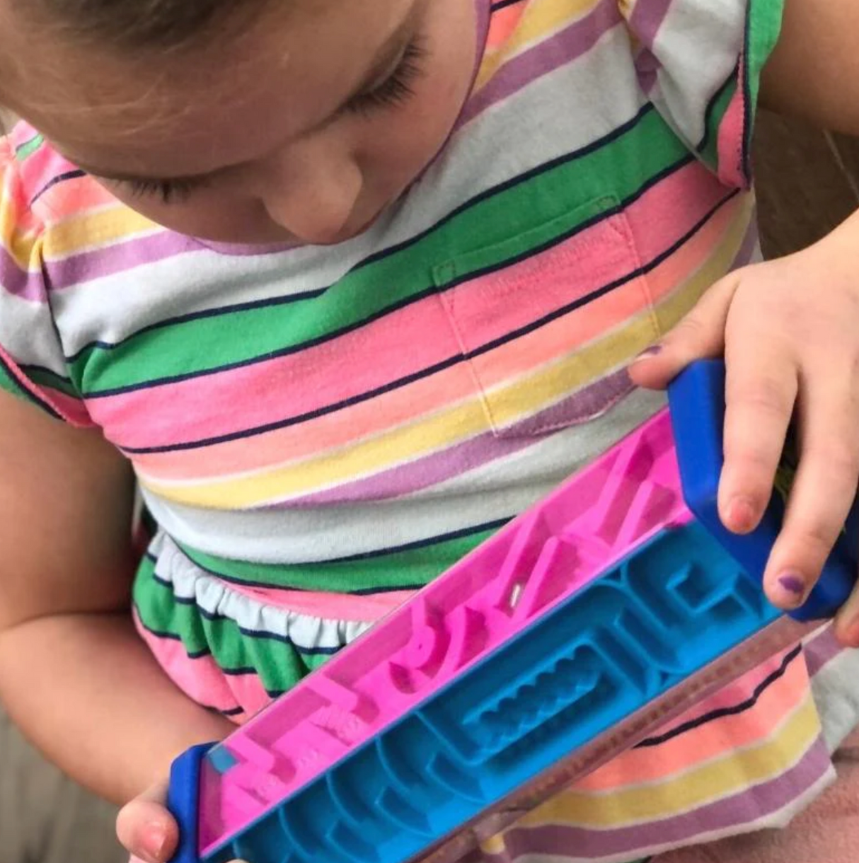 Child playing with Zoomi The Hexagon Maze handheld puzzle game with colorful twisting maze panels.