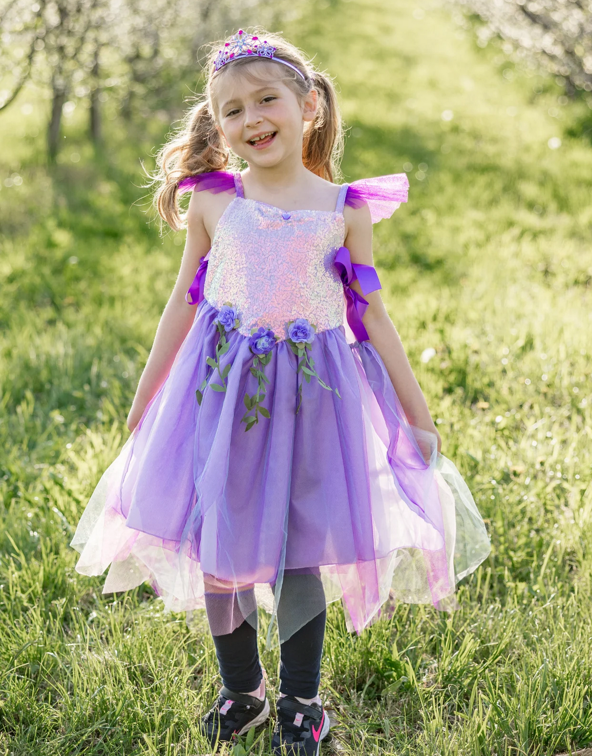Little girl outdoors wearing the Lilac Sequins Fairy Tunic | Size 5-6 with sparkly sequins and purple ribbon details.