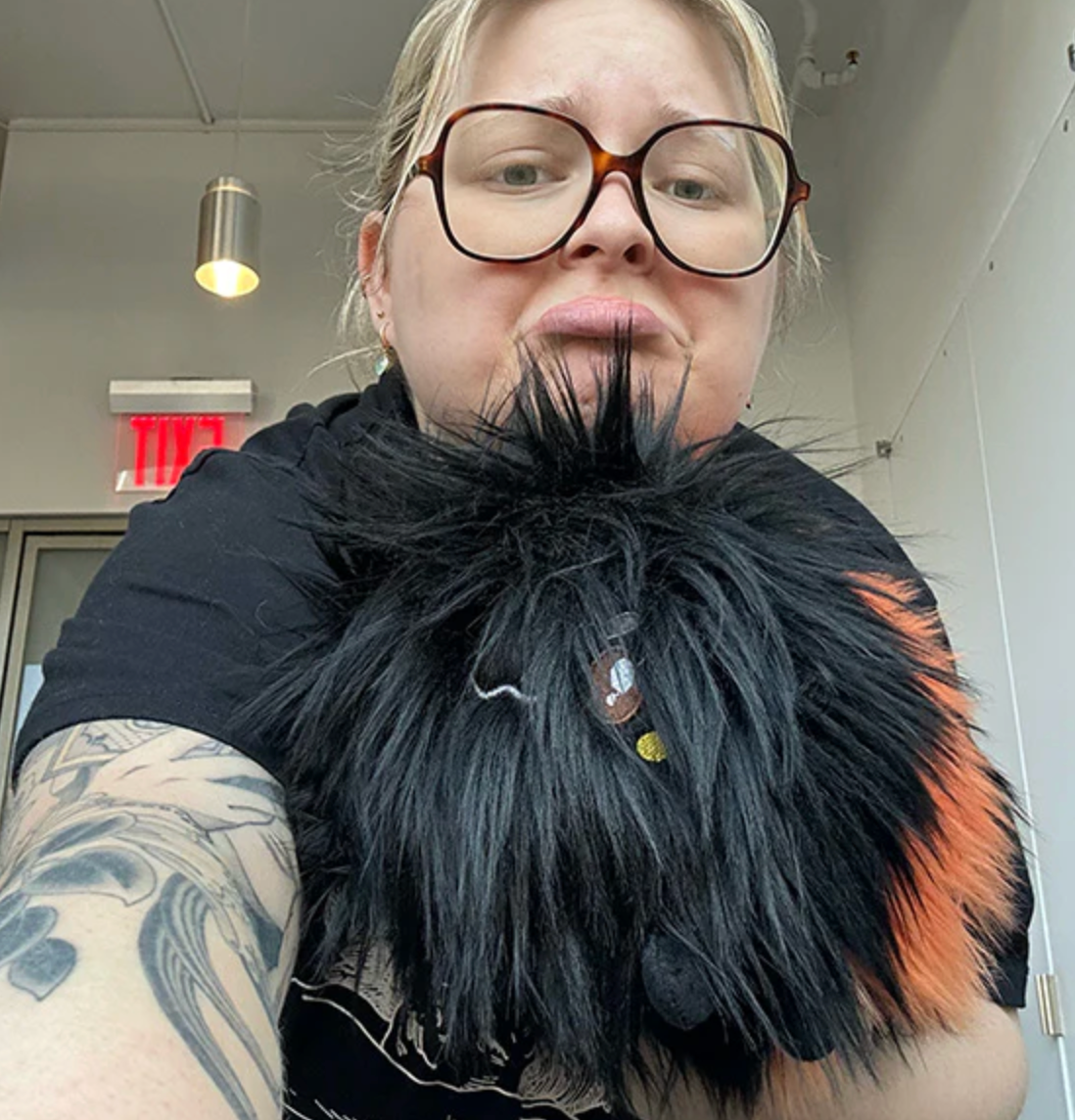 Person holding a Wooly Caterpillar Mini plush with black and orange segments indoors.