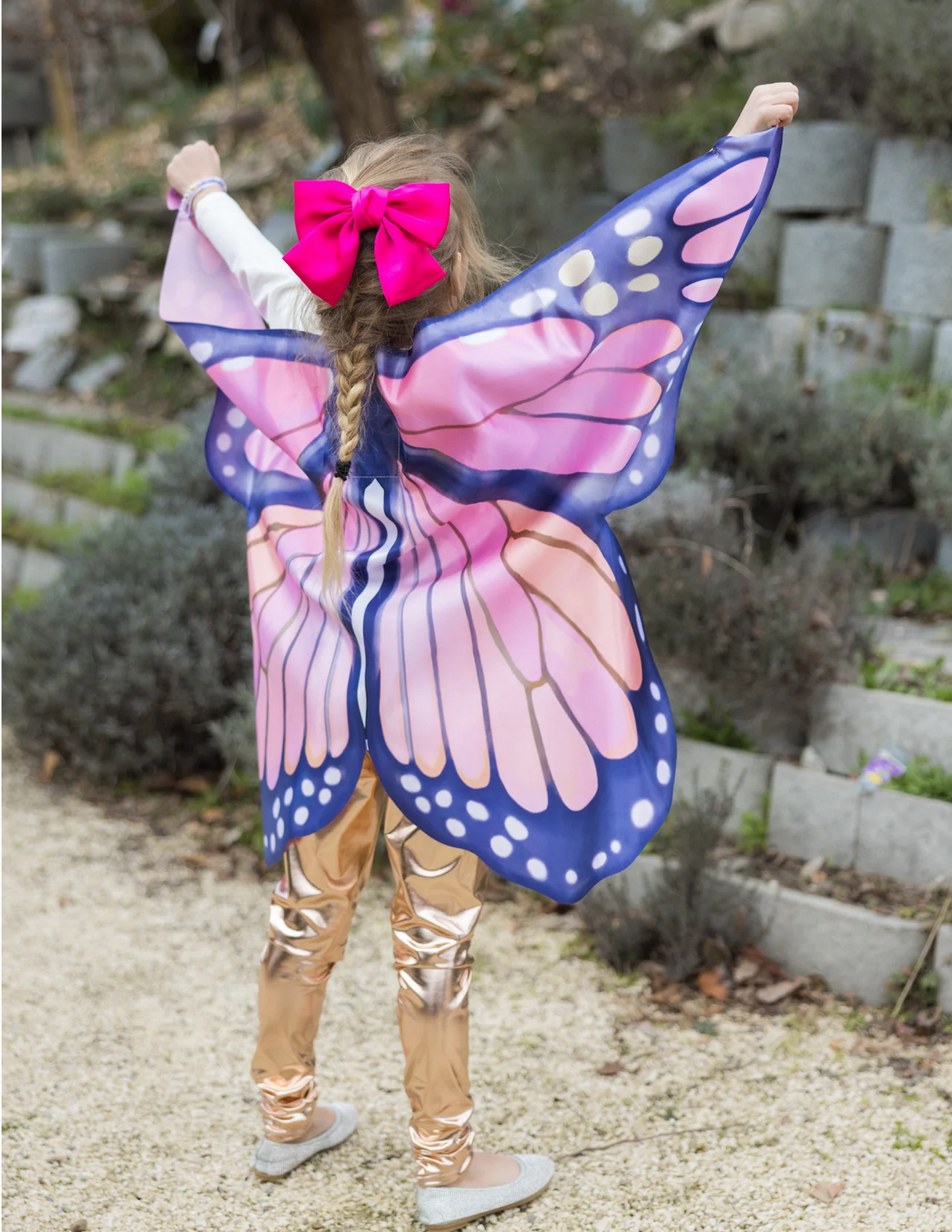 Child wearing Soft Wings | Mystical Monarch with vibrant pink and purple butterfly wings and a bright pink bow outdoors.