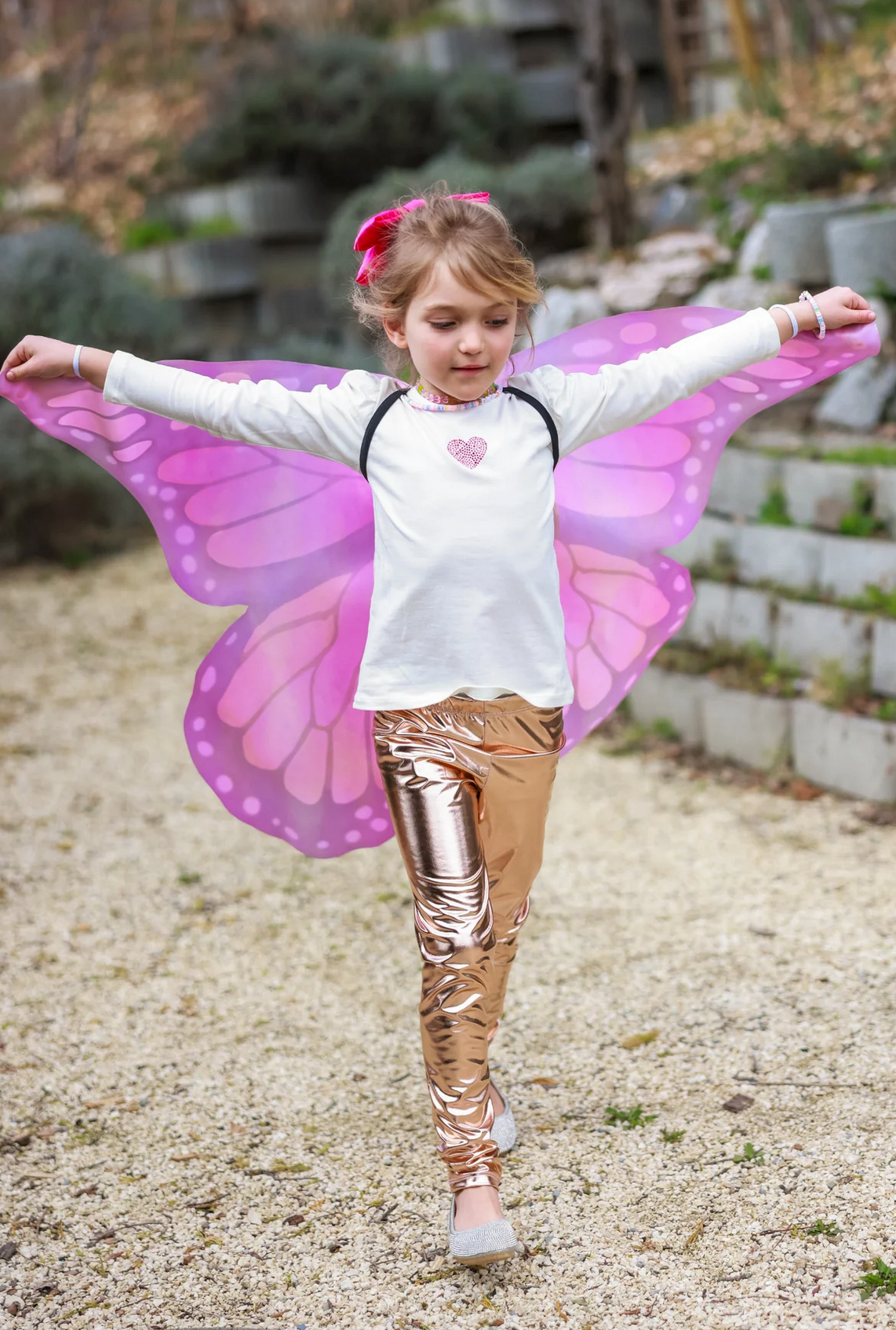 Young girl wearing Soft Wings | Mystical Monarch butterfly wings with vibrant pink and purple patterns outdoors.