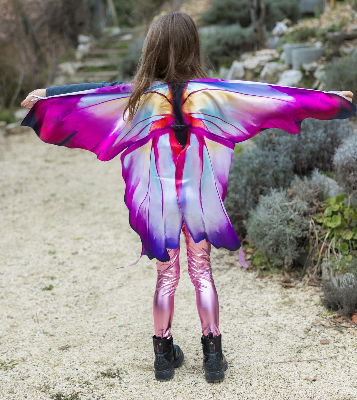 Child wearing vibrant pink and purple Soft Wings | Ombre Butterfly with gradient hues and flowing design outdoors.