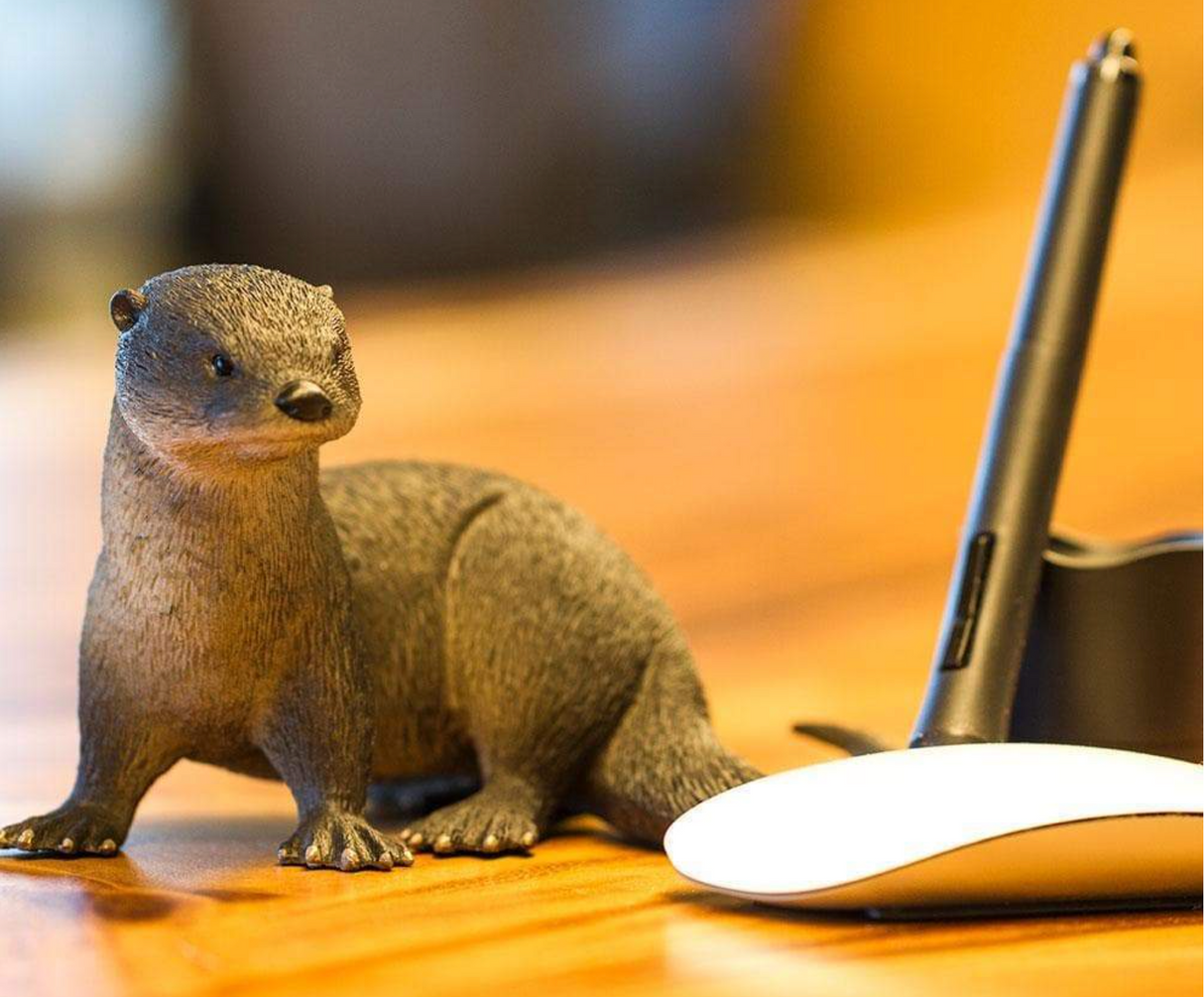 River Otter figurine showing detailed brown semi-aquatic mammal next to a computer mouse and pen stand.