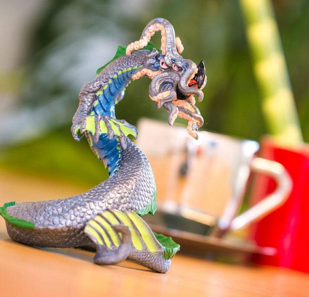 Leviathan figurine showing detailed four-eyed sea serpent with tentacles, coiled and ready to strike atop a wooden surface.