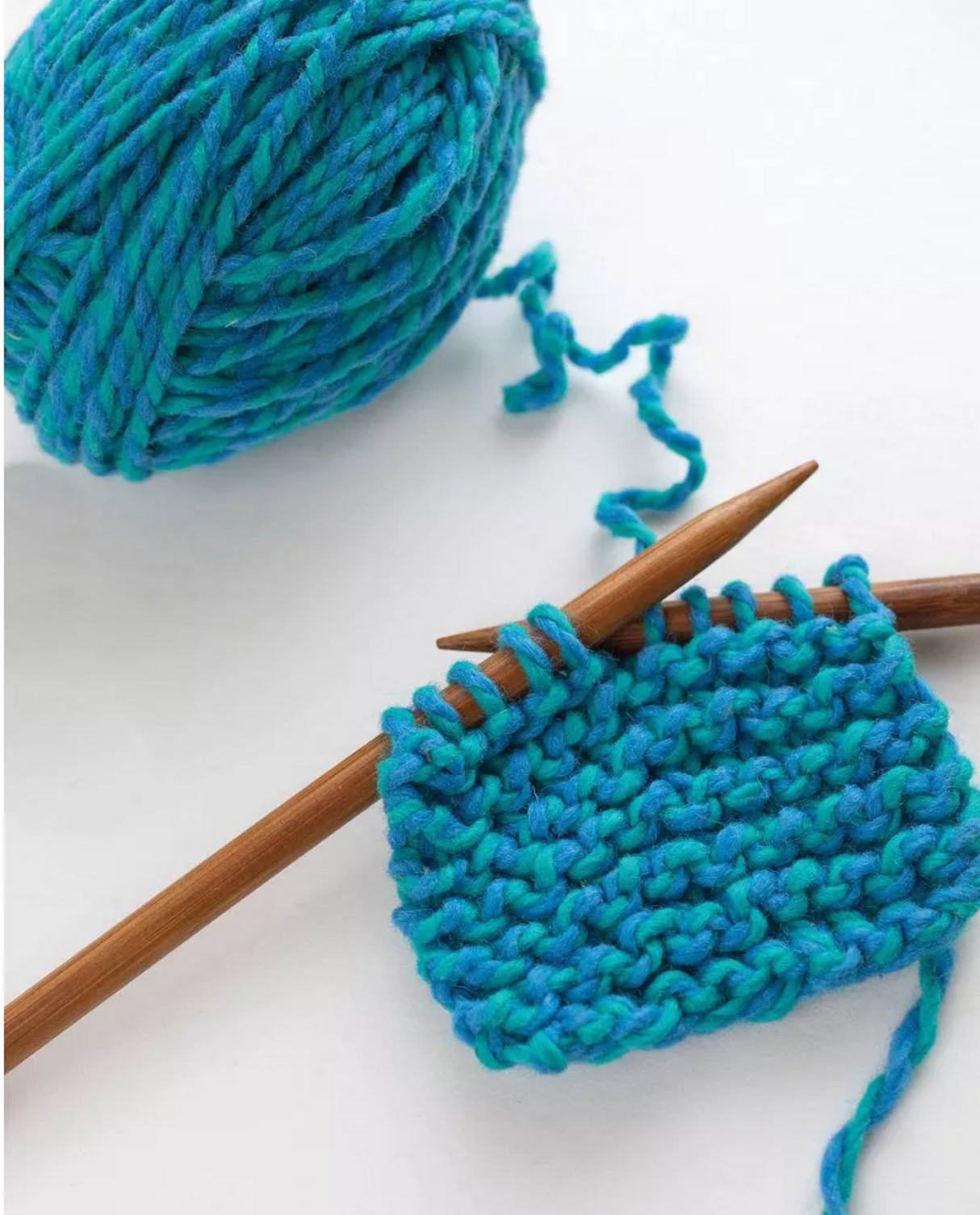 Discover Knitting Scarf Kit | Blue showing blue wool yarn and wooden needles with a knitted garter stitch swatch.