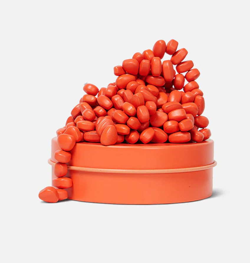 Speks. Matte. Mini Crags. Coral. shows small coral-colored ferrite putty pieces overflowing from a matching tin container.